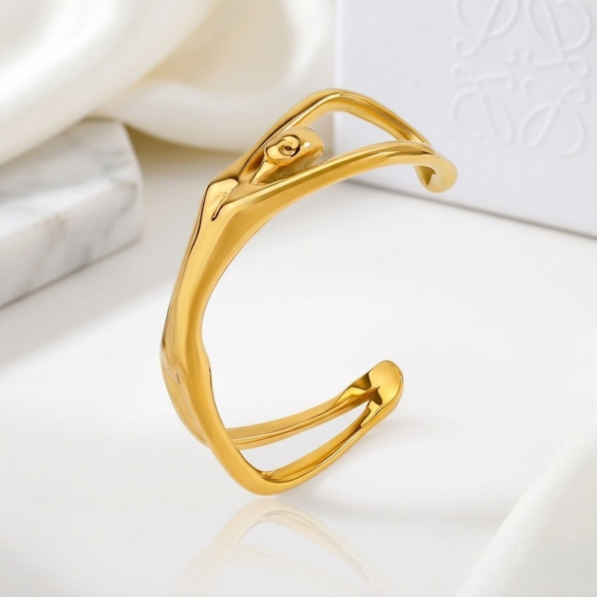 BEHI MILANO Devika Bracelet — gold organic line body cuff displayed on white marble slab