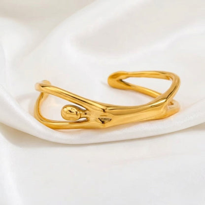 BEHI MILANO Devika Bracelet — gold abstract cuff standing on draped white silk cloth