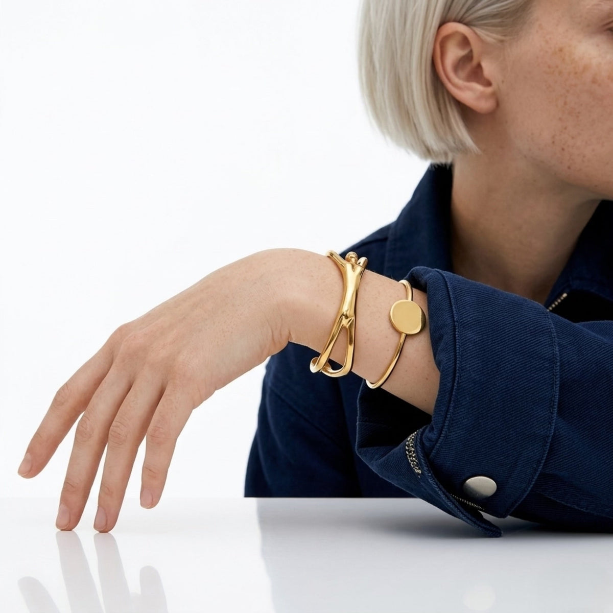 BEHI MILANO Devika Bracelet — model wearing gold sculptural cuff stacked with gold disc bracelet