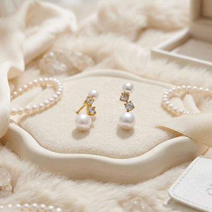 BEHI MILANO Diana Earrings — pair of gold pearl studs displayed on off-white ceramic tray with pearls
