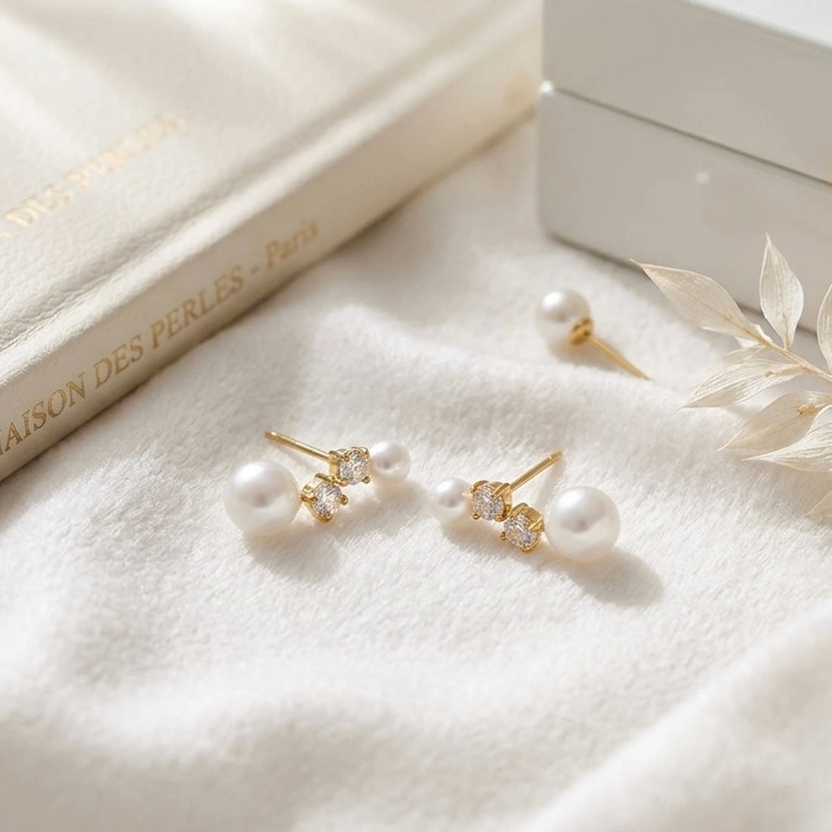 BEHI MILANO Diana Earrings — gold pearl and zircon stud earrings resting on white silk fabric