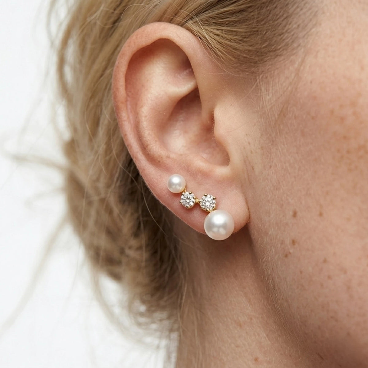 BEHI MILANO Diana Earrings — close-up of gold pearl cluster drop studs worn on earlobe