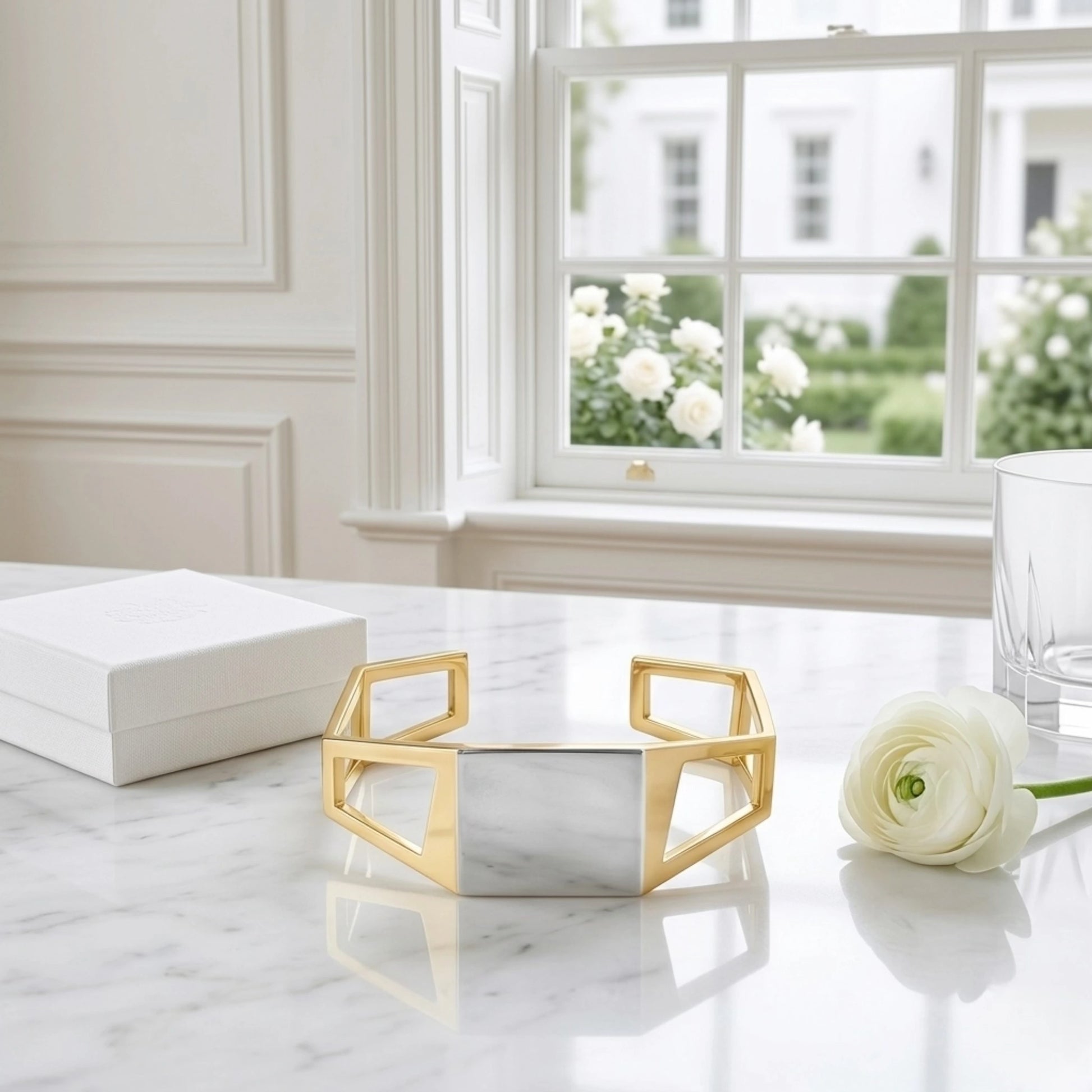 BEHI MILANO Dimitra Bracelet — gold two-tone geometric cuff displayed on marble windowsill with white rose