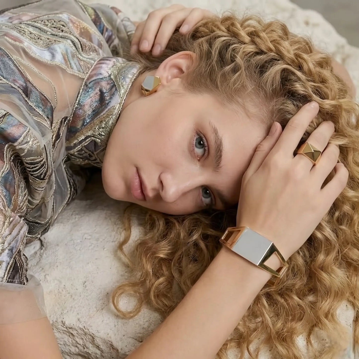 BEHI MILANO Dimitra Bracelet — model resting head on arm wearing architectural gold cuff