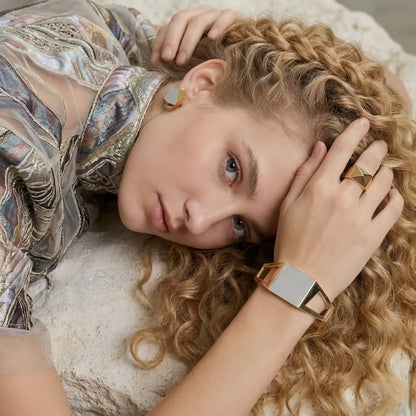 BEHI MILANO Dimitra Bracelet — model resting head on arm wearing architectural gold cuff