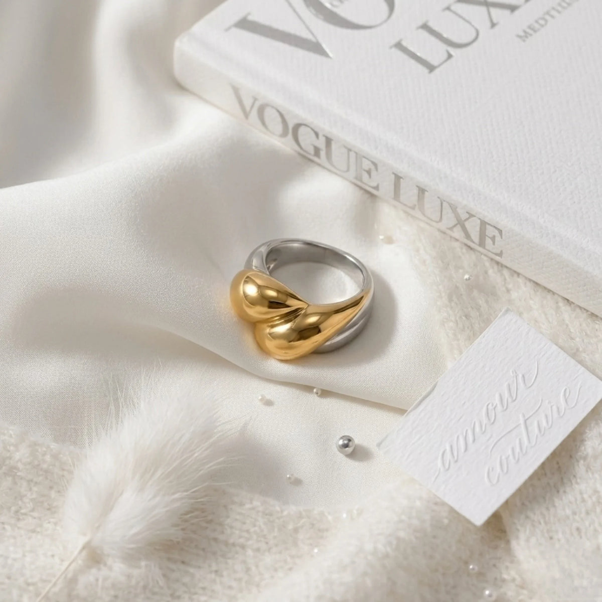 BEHI MILANO Disha Ring — close-up flat lay of two-tone abstract heart ring on white silk cloth