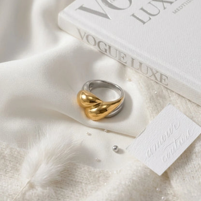 BEHI MILANO Disha Ring — close-up flat lay of two-tone abstract heart ring on white silk cloth