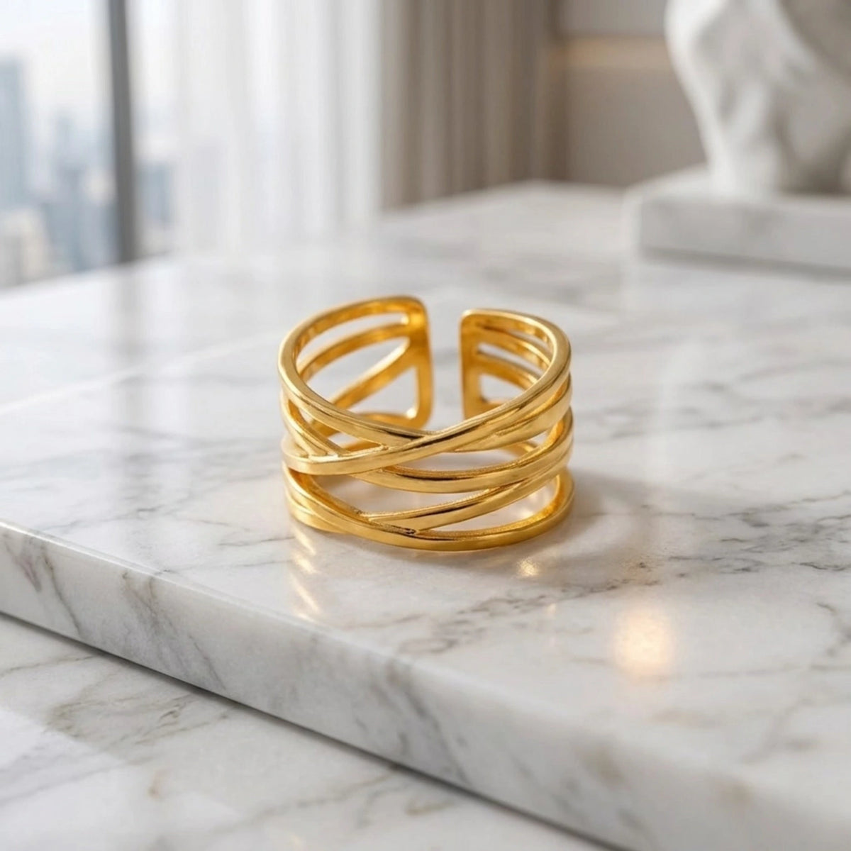 BEHI MILANO Eden Ring — 18k gold multi-layer ring displayed on white marble table