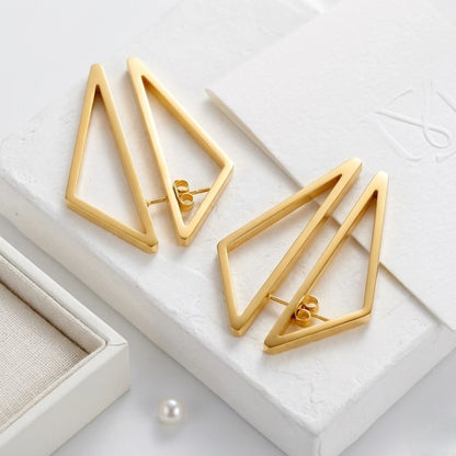 BEHI MILANO Elif Earrings — gold geometric drop earrings displayed on white marble box lid