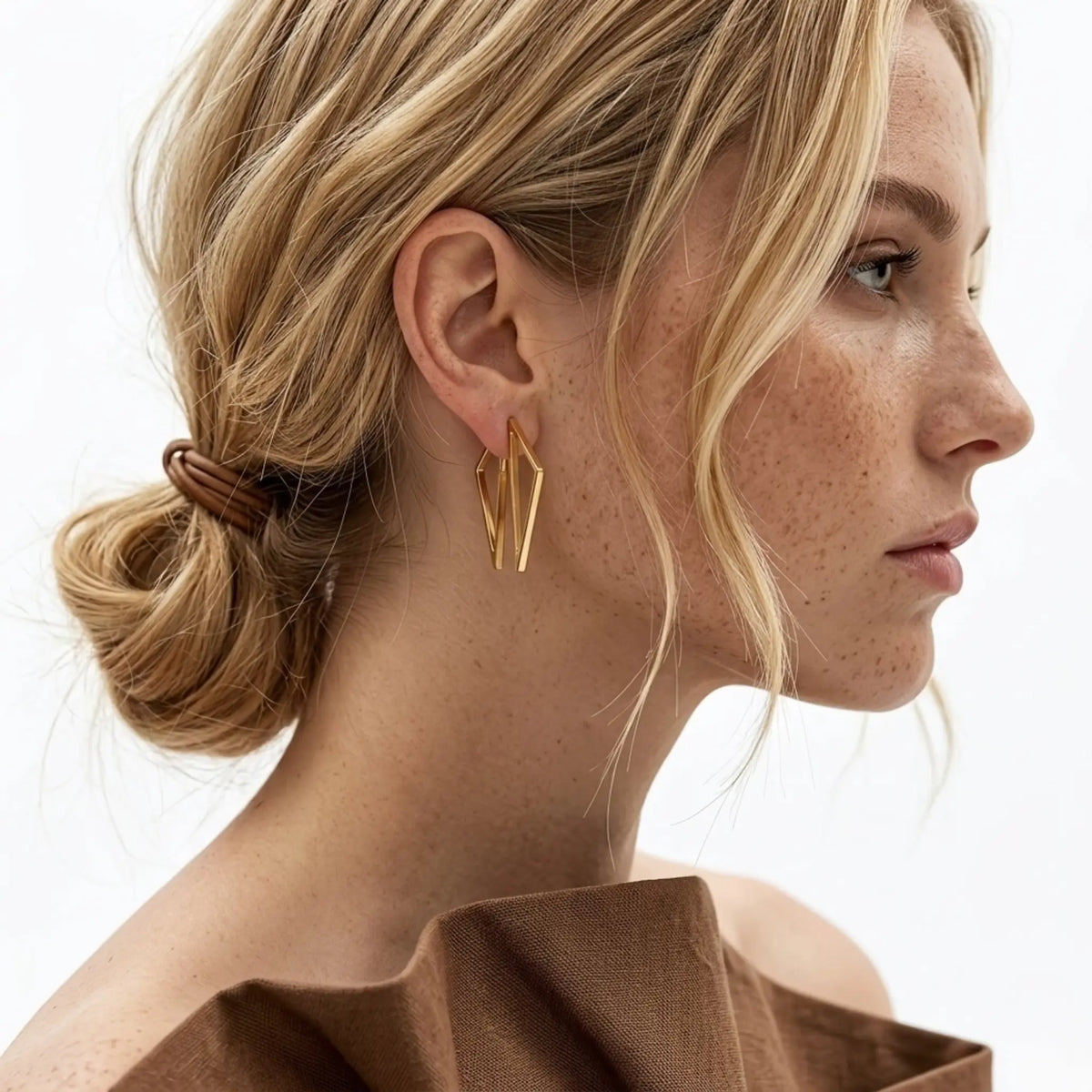 BEHI MILANO Elif Earrings — model wearing gold geometric polygonal earrings with low bun hairstyle