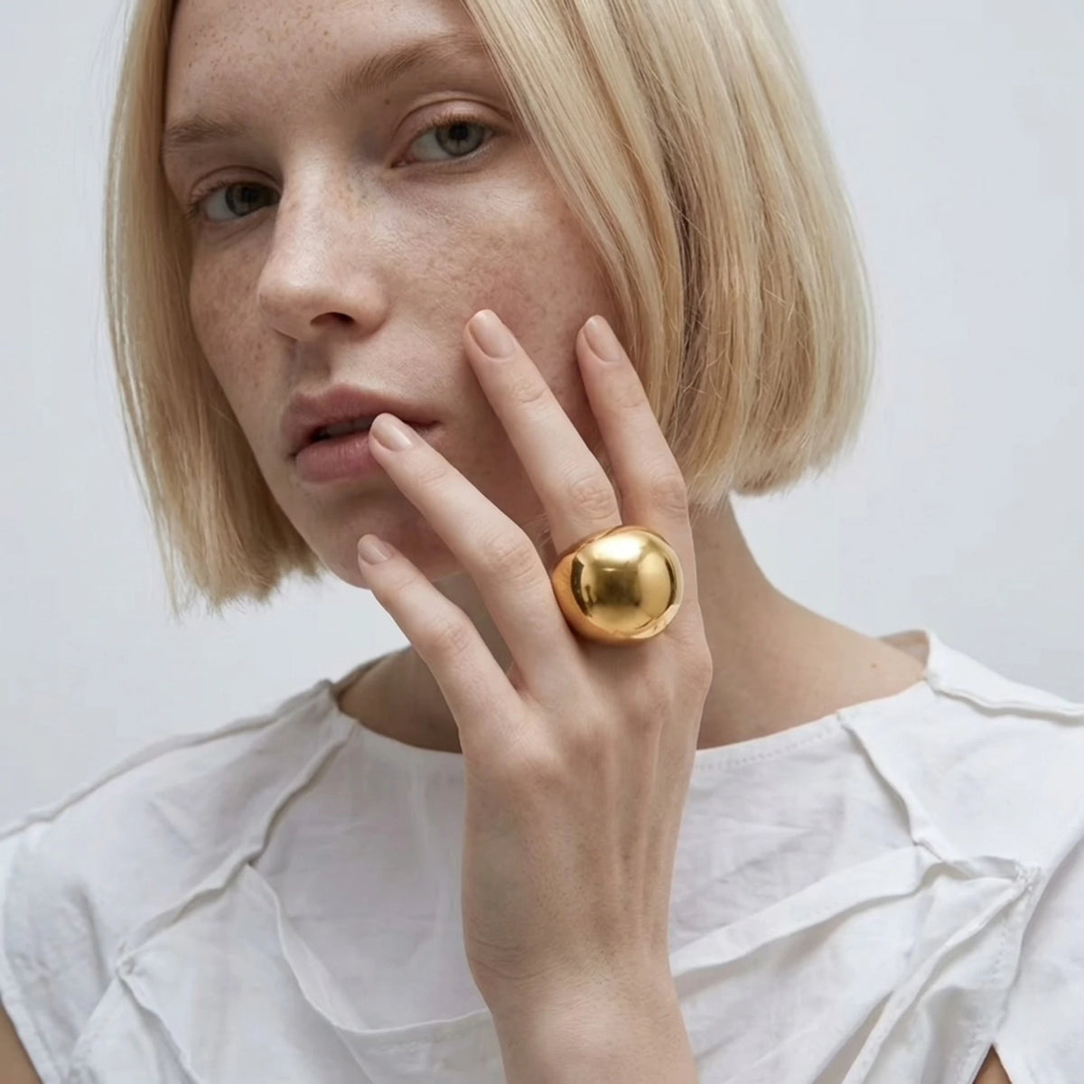 BEHI MILANO Elika Ring — model wearing chunky gold orb ring with white linen top