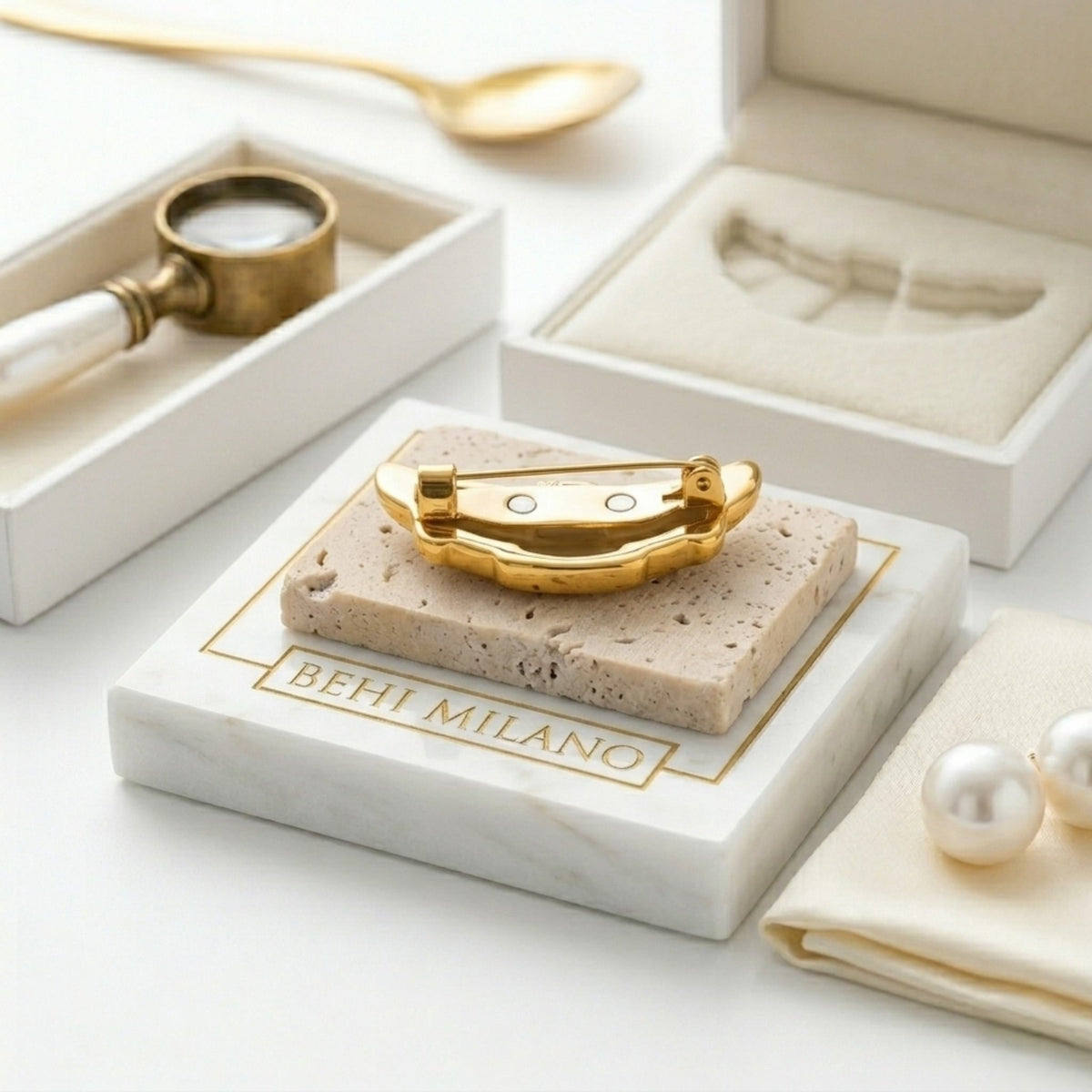 BEHI MILANO Elisa Brooch — angled detail of 18k gold croissant brooch on marble block