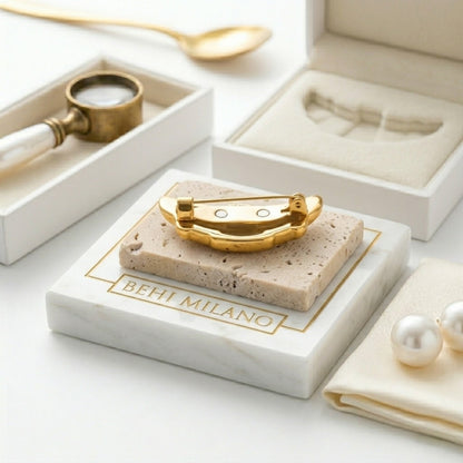 BEHI MILANO Elisa Brooch — angled detail of 18k gold croissant brooch on marble block