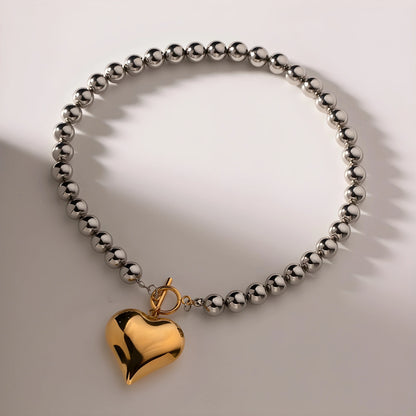 BEHI MILANO Emma Choker — gold heart charm and silver bead necklace with soft shadow lighting