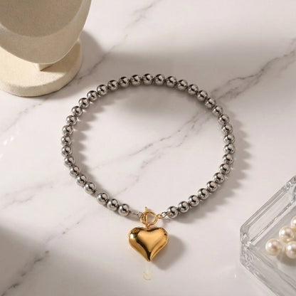 BEHI MILANO Emma Choker — two-tone heart pendant choker displayed on light marble