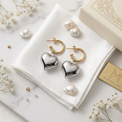 BEHI MILANO Emma Earrings — gold and silver puffy heart drop earrings on white fabric