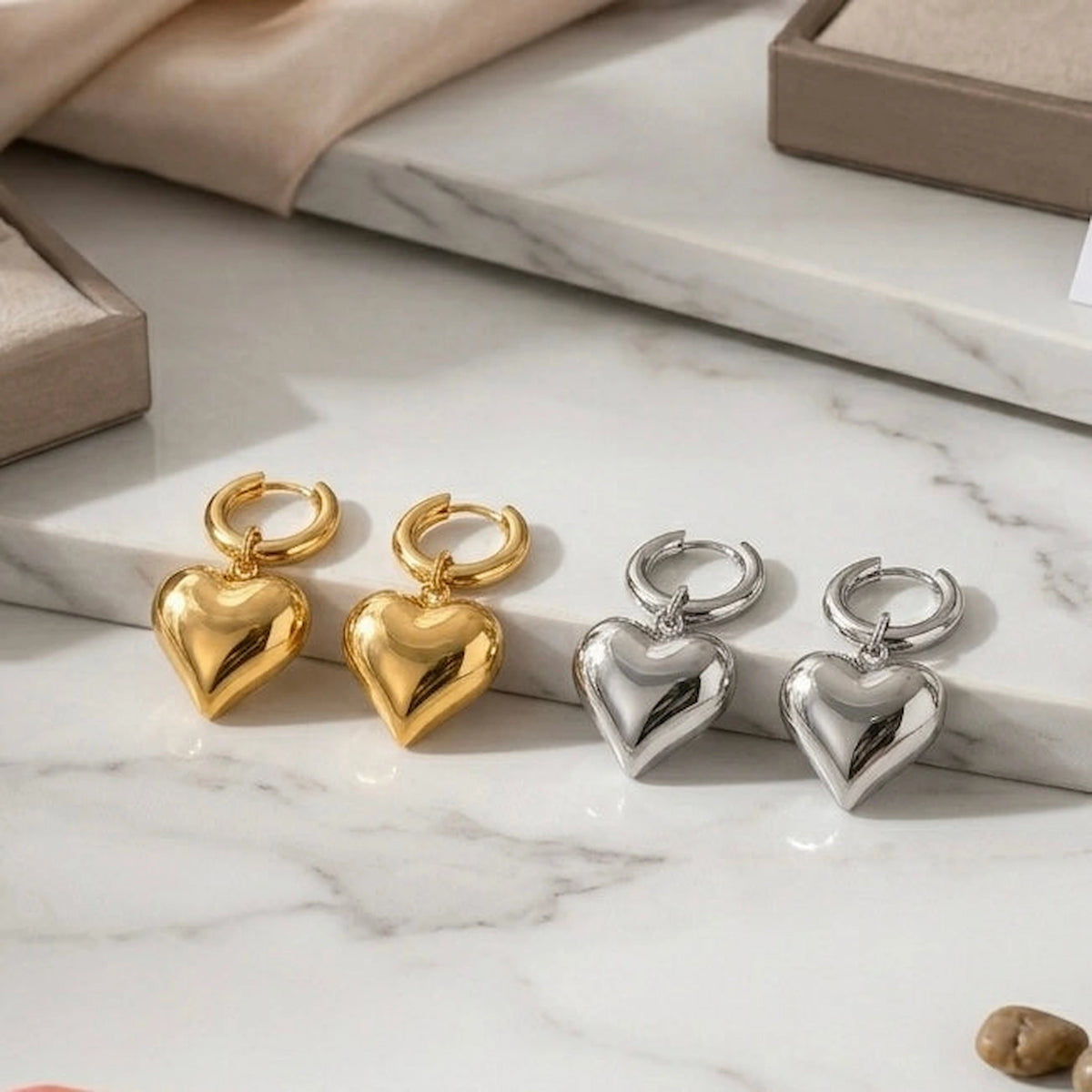 BEHI MILANO Emma Hoop Earrings — gold and silver puffy heart hoop pairs displayed on white marble