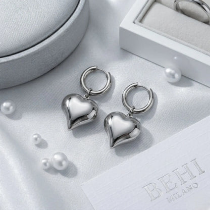 BEHI MILANO Emma Hoop Earrings — silver puffy heart drop hoop earrings on grey satin display tray