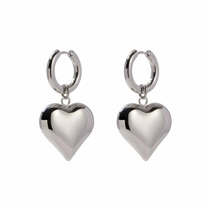 BEHI MILANO Emma Hoop Earrings — silver puffy heart drop huggie hoop earrings on white background