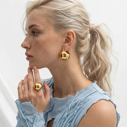 BEHI MILANO Erika Earrings — model with blonde ponytail wearing chunky gold sphere earrings