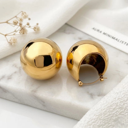 BEHI MILANO Erika Earrings — chunky gold spherical dome earrings on white marble display tray