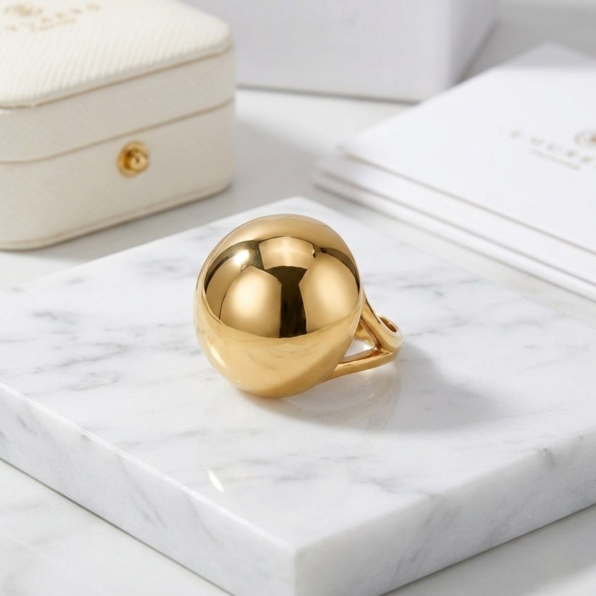 BEHI MILANO Erika Ring — 18k gold bubble dome ring on marble surface with jewelry pouch