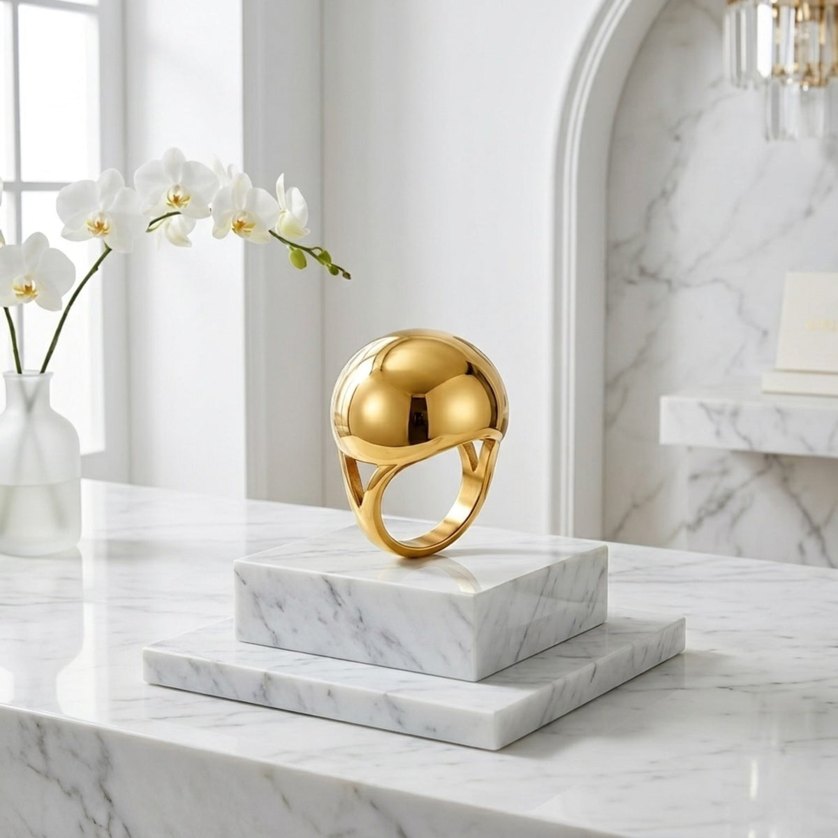 BEHI MILANO Erika Ring — gold spherical dome ring upright on white marble pedestal