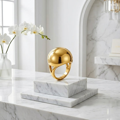 BEHI MILANO Erika Ring — gold spherical dome ring upright on white marble pedestal