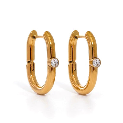 BEHI MILANO Eva Earrings — 18k gold elongated oval hoop earrings with clear zircon stone on white background
