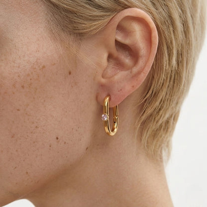 BEHI MILANO Eva Earrings — close-up of model ear displaying 18k gold oval huggie hoop with zircon
