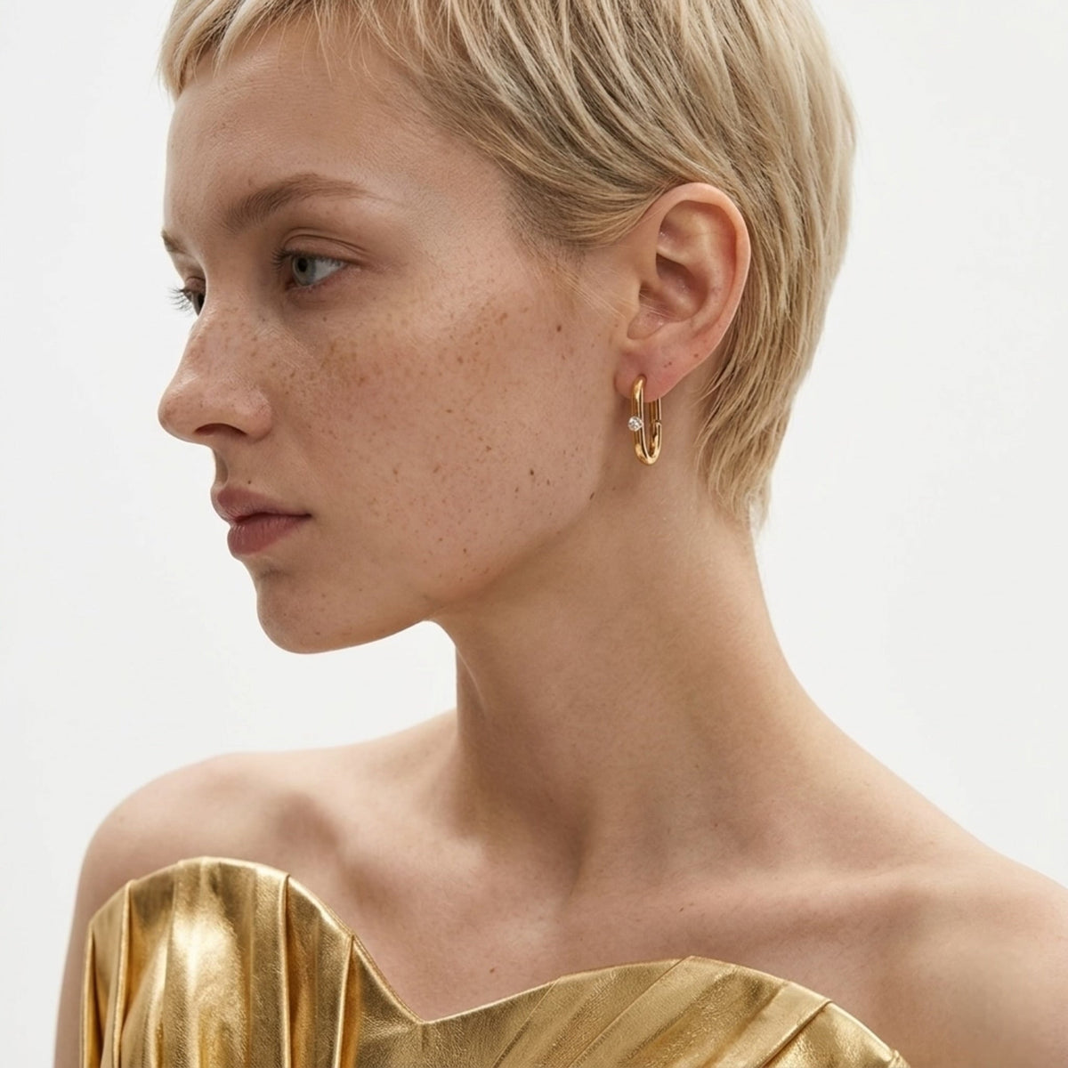 BEHI MILANO Eva Earrings — model with short blonde hair wearing gold oval zircon hoop earrings
