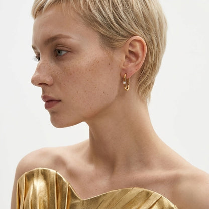 BEHI MILANO Eva Earrings — model with short blonde hair wearing gold oval zircon hoop earrings