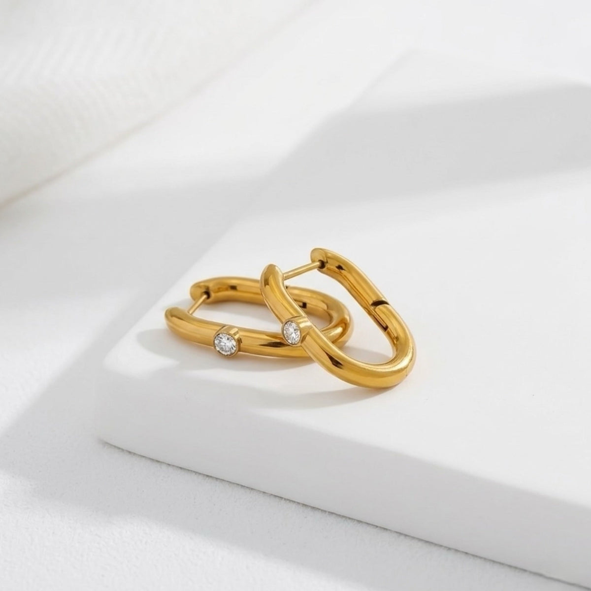 BEHI MILANO Eva Earrings — 18k gold oval gem hoop earrings resting on marble display tray