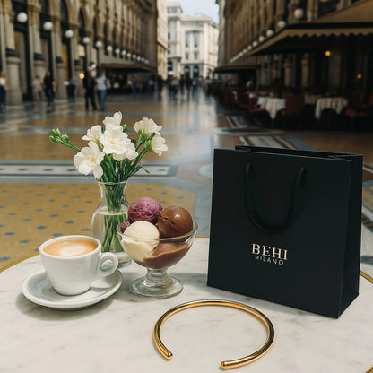 BEHI MILANO Flavia Choker — gold collar necklace on outdoor cafe table with BEHI MILANO luxury shopping bag in Milan