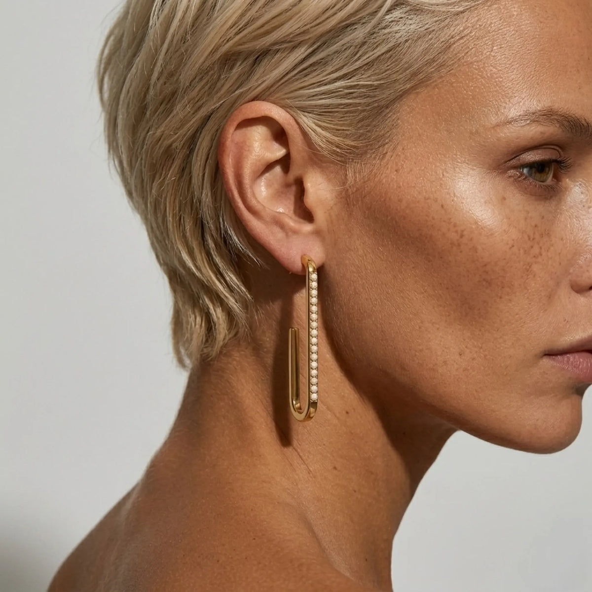 BEHI MILANO Floriana Earrings — short blonde hair model wearing 18k gold long pearl drop earring