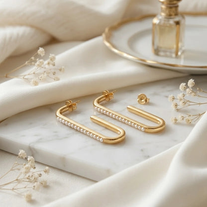 BEHI MILANO Floriana Earrings — gold pearl drop earrings flat lay on marble with delicate dried flowers