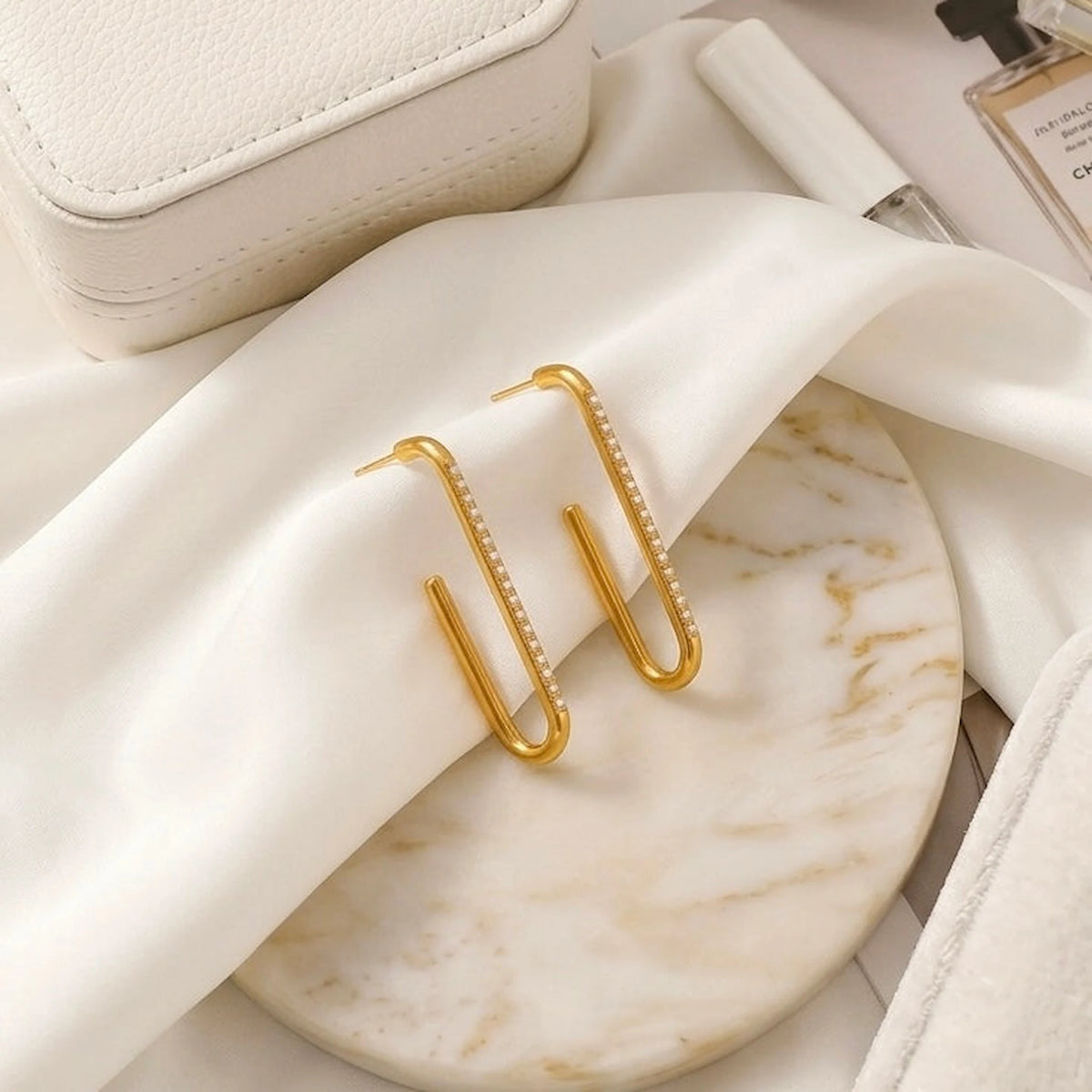 BEHI MILANO Floriana Earrings — gold statement drop earrings on round marble dish with soft satin cloth