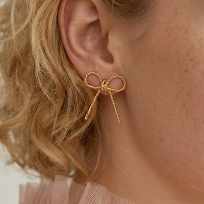 BEHI MILANO Francy Earrings — close-up of model ear showing 18k gold twisted bow stud earring