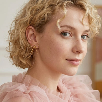 BEHI MILANO Francy Earrings — curly blonde model wearing 18k gold twisted bow earring in pink top