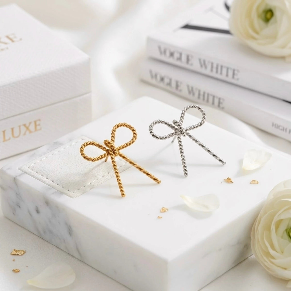 BEHI MILANO Francy Earrings — gold and silver twisted bow statement earrings displayed together on marble