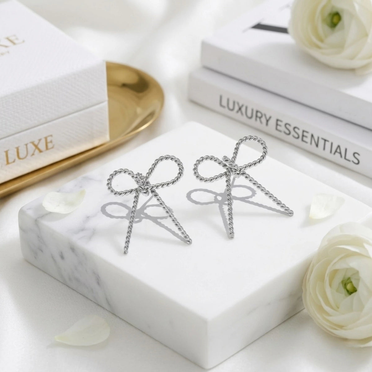 BEHI MILANO Francy Earrings — silver twisted rope bow stud earrings on white marble tray