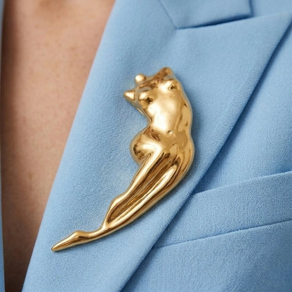 BEHI MILANO Galina Brooch — close-up of gold abstract figure brooch pinned on light blue blazer lapel