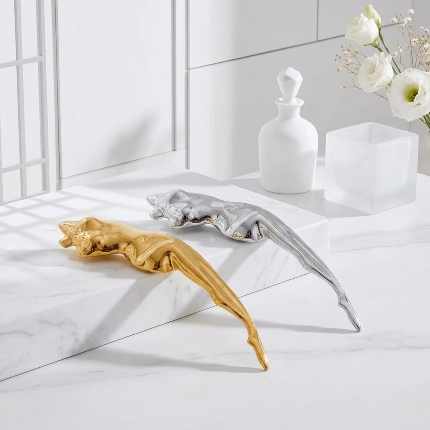 BEHI MILANO Galina Brooch — gold and silver abstract figure brooches displayed on white marble surface