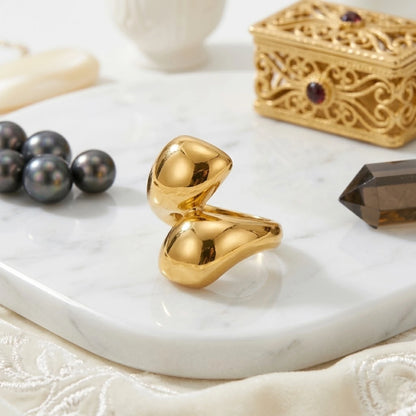 BEHI MILANO Garlita Ring — gold liquid teardrop ring on white marble tray with black pearls