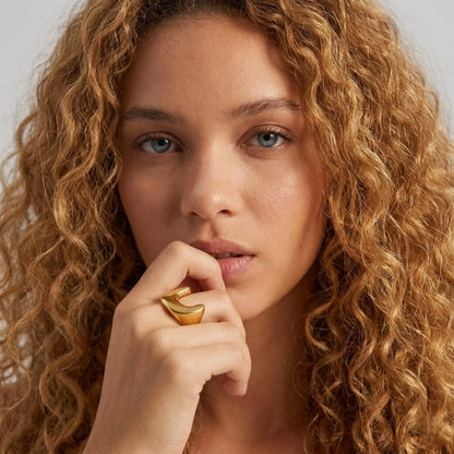 BEHI MILANO Giusy Ring — curly blonde model wearing gold sculptural ring touching face