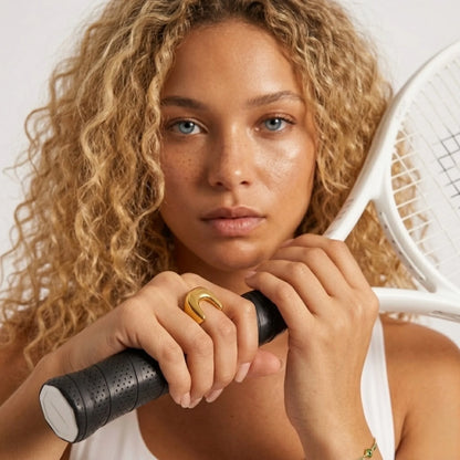 BEHI MILANO Giusy Ring — blonde model on tennis court holding white tennis racket wearing gold statement ring