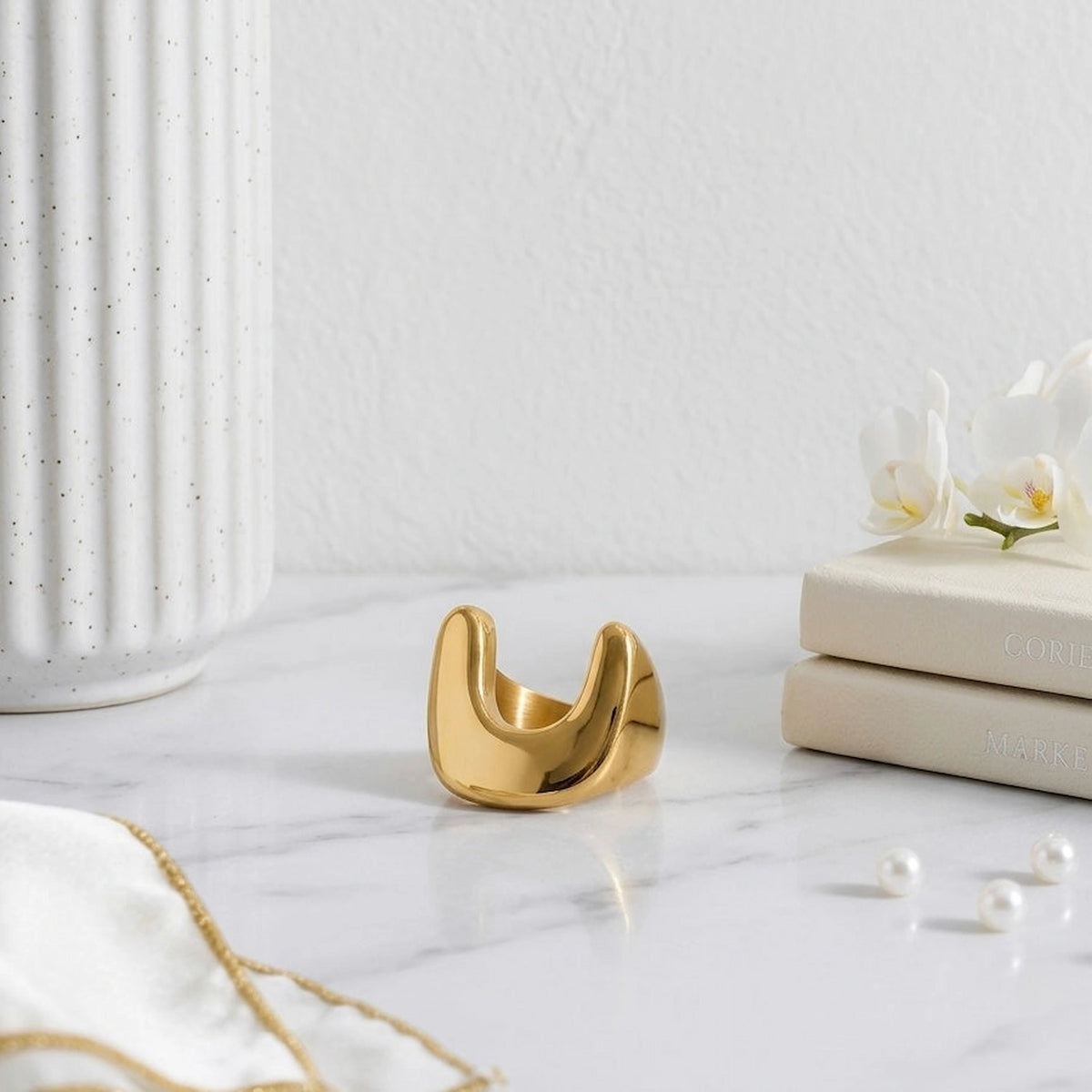 BEHI MILANO Giusy Ring — 18k gold dipped ring displayed on white marble surface in front of fluted column