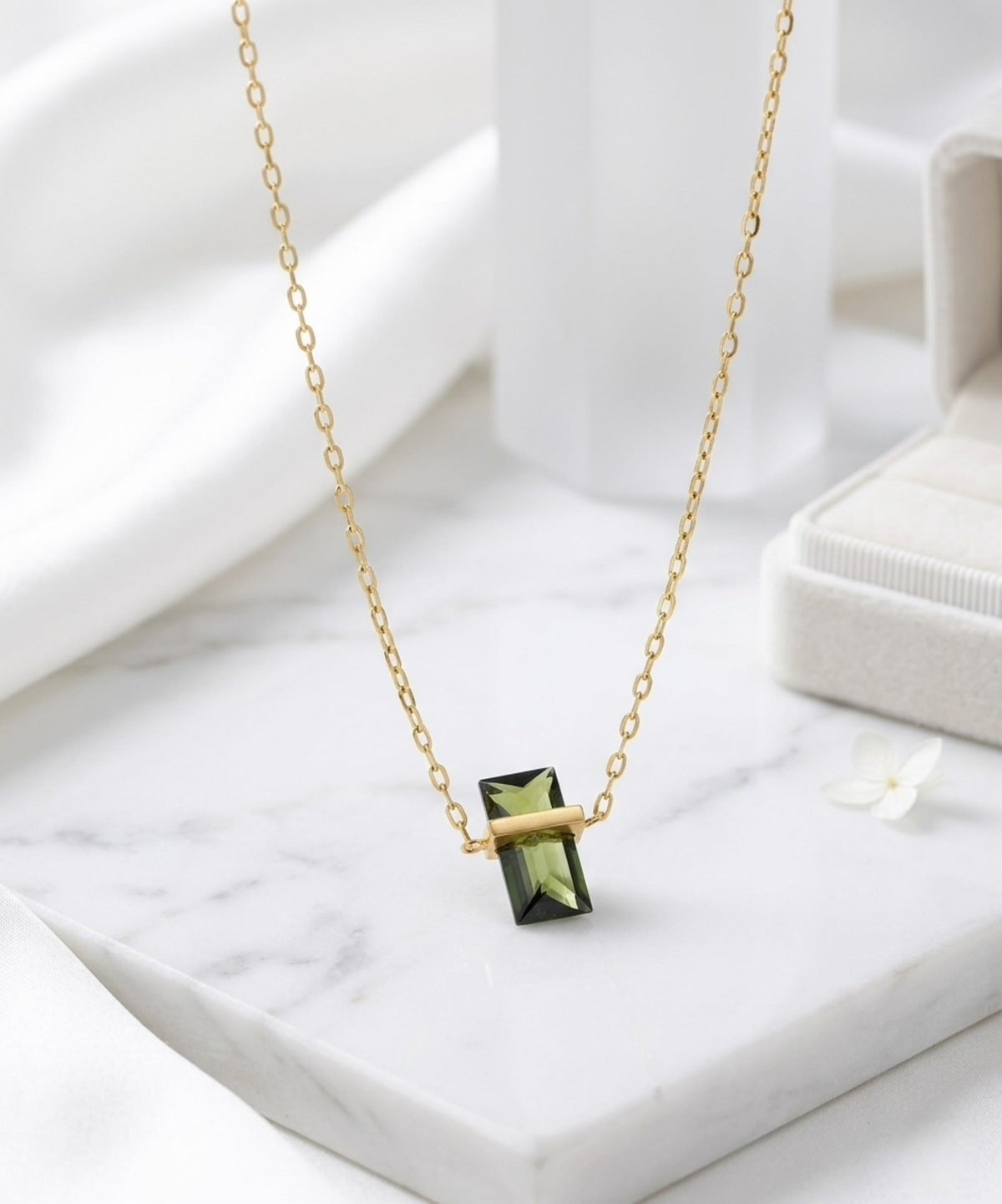 BEHI MILANO Glinka Necklace — close-up angle view of green zircon gemstone pendant on white surface