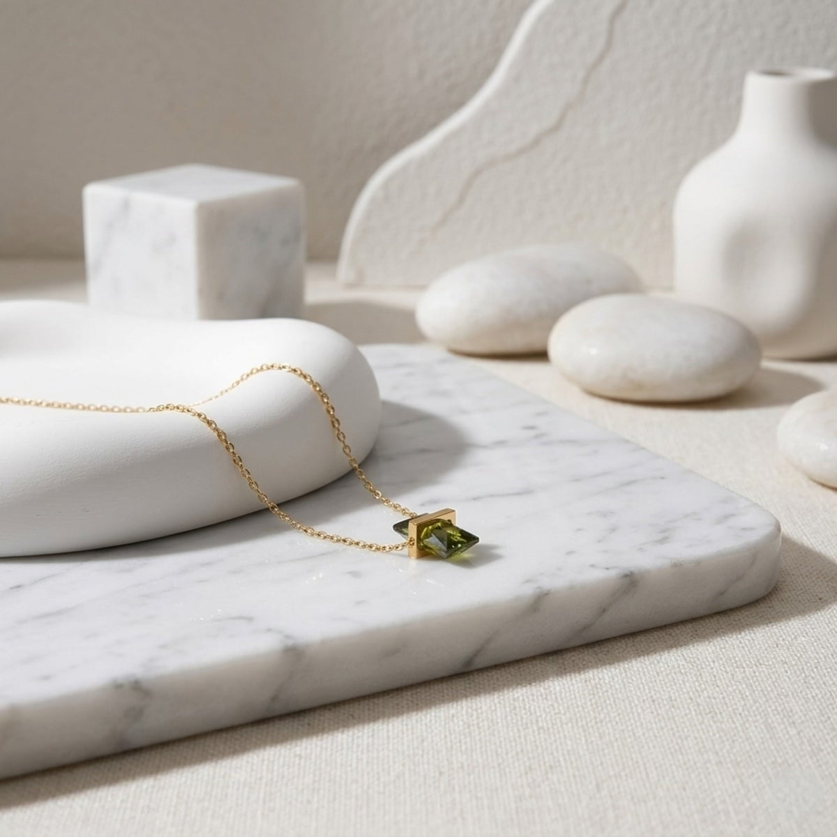 BEHI MILANO Glinka Necklace — green zircon pendant necklace displayed on white marble with stones