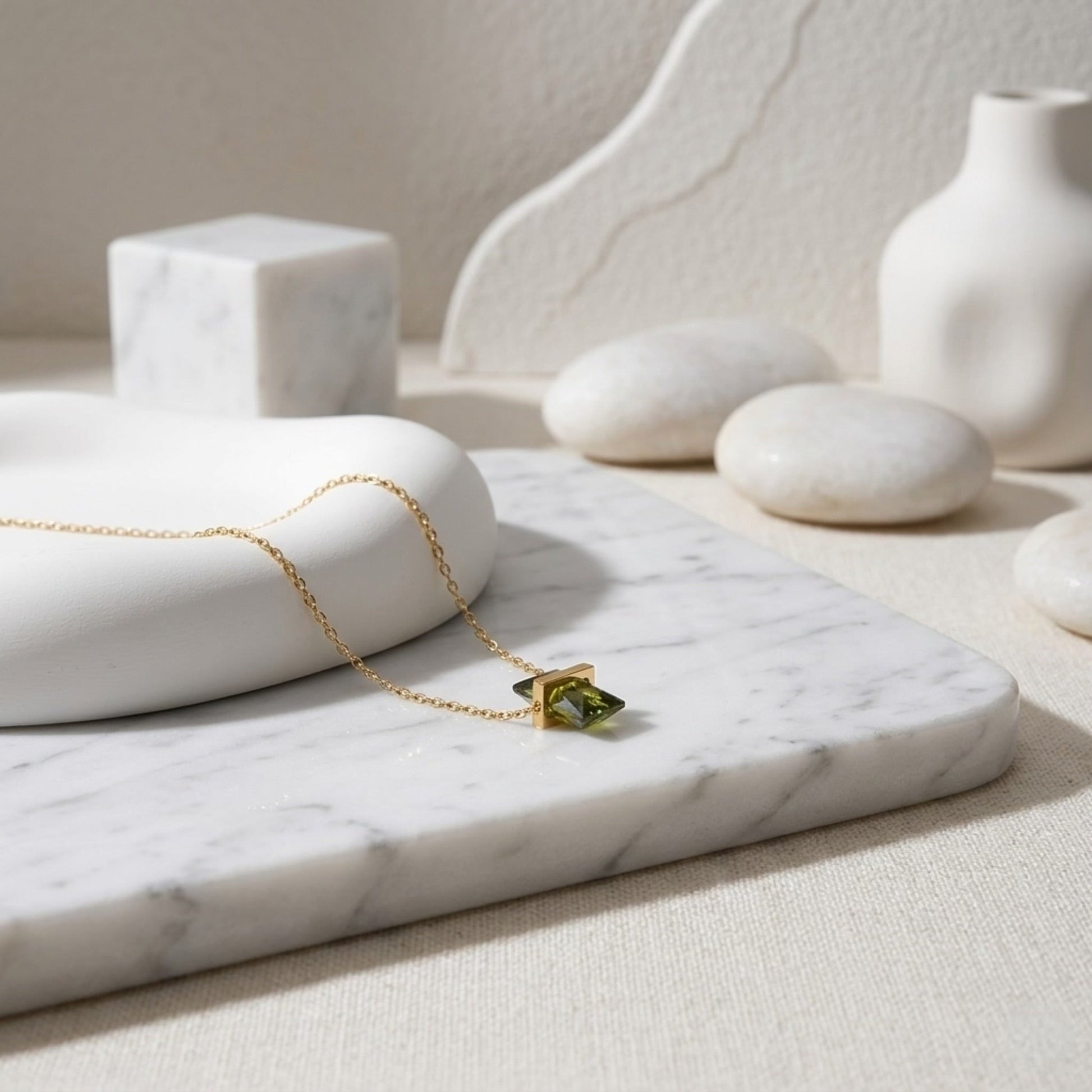 BEHI MILANO Glinka Necklace — green zircon pendant necklace displayed on white marble with stones